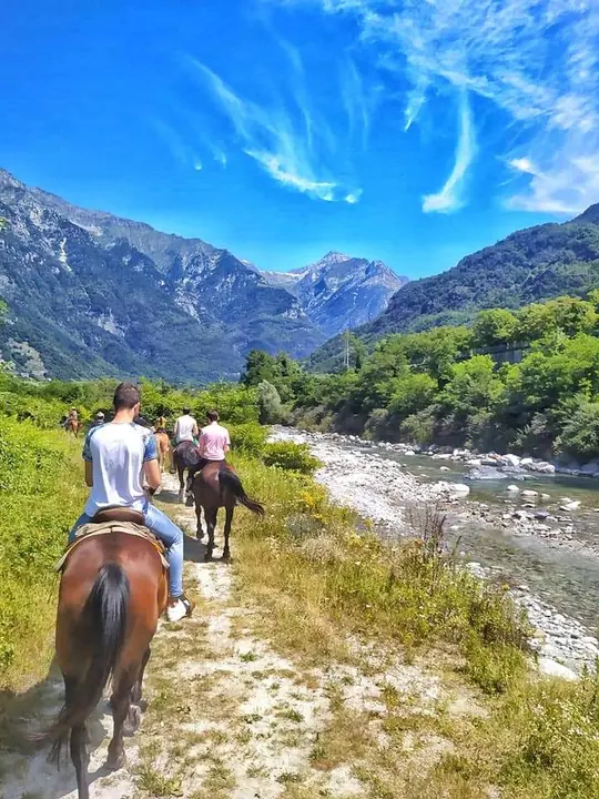 Gruppo a cavallo lungo il sentiero sul fiume